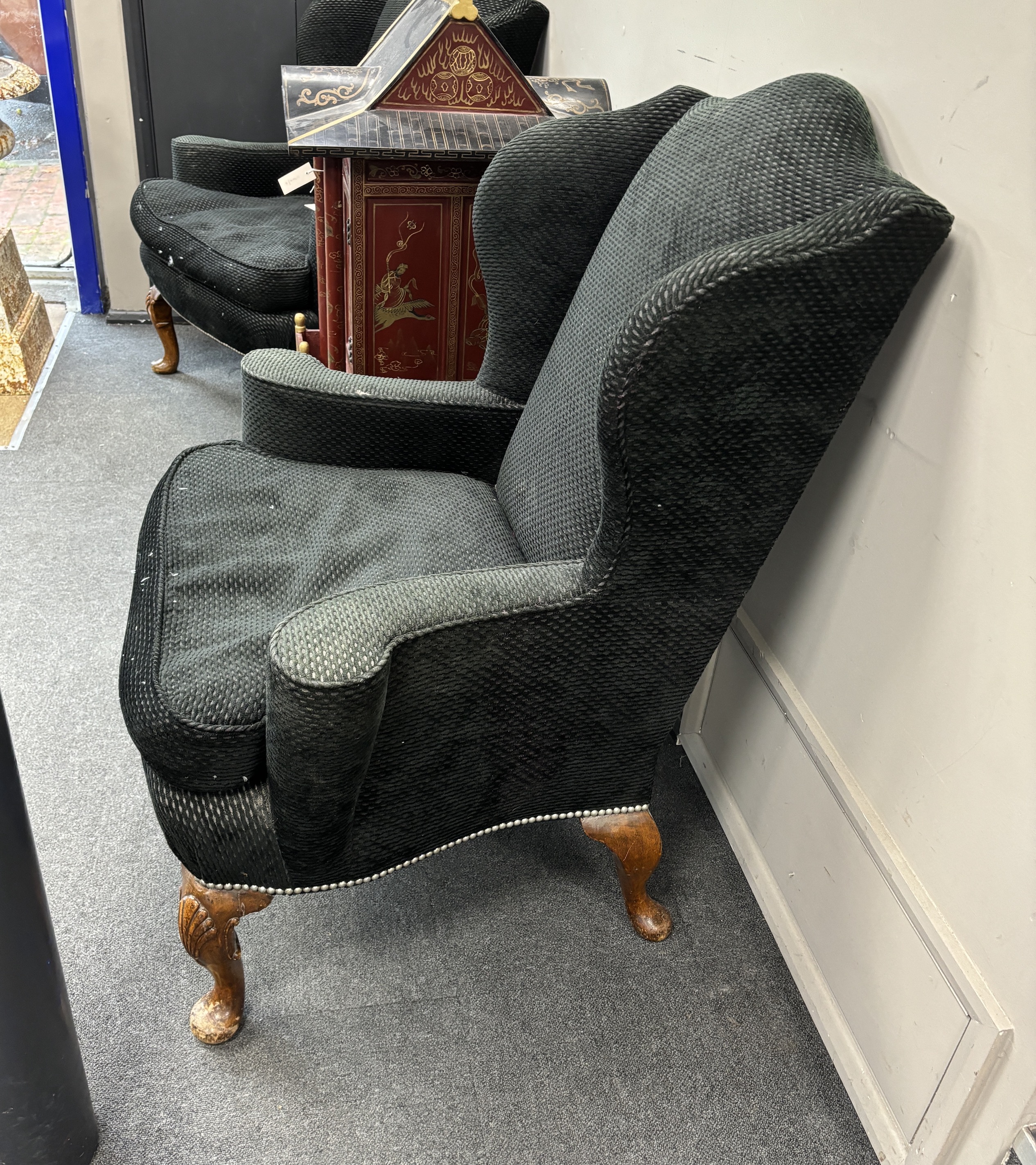 A pair of Queen Anne revival upholstered wing back armchairs on shell carved cabriole legs, width 88cm, depth 78cm, height 108cm.